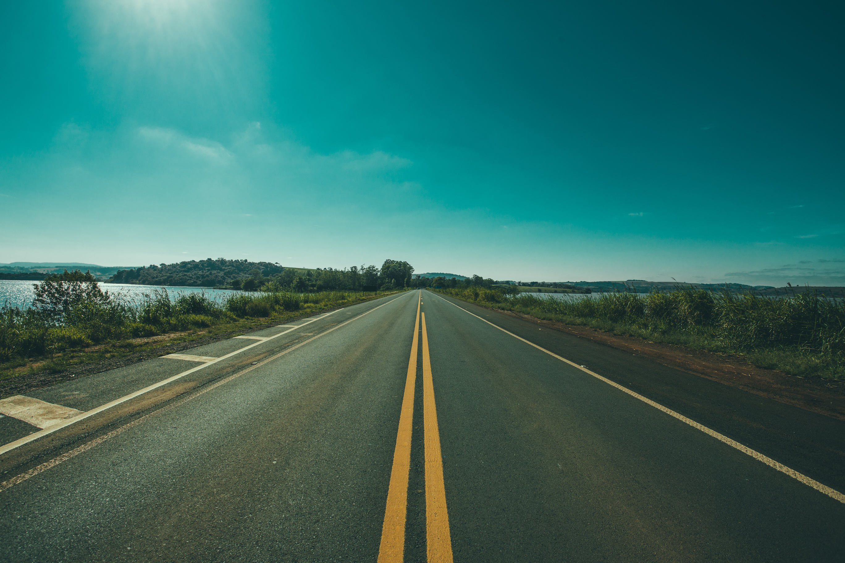 Panoramic Photography of Road Between Grasses and Body of Waters